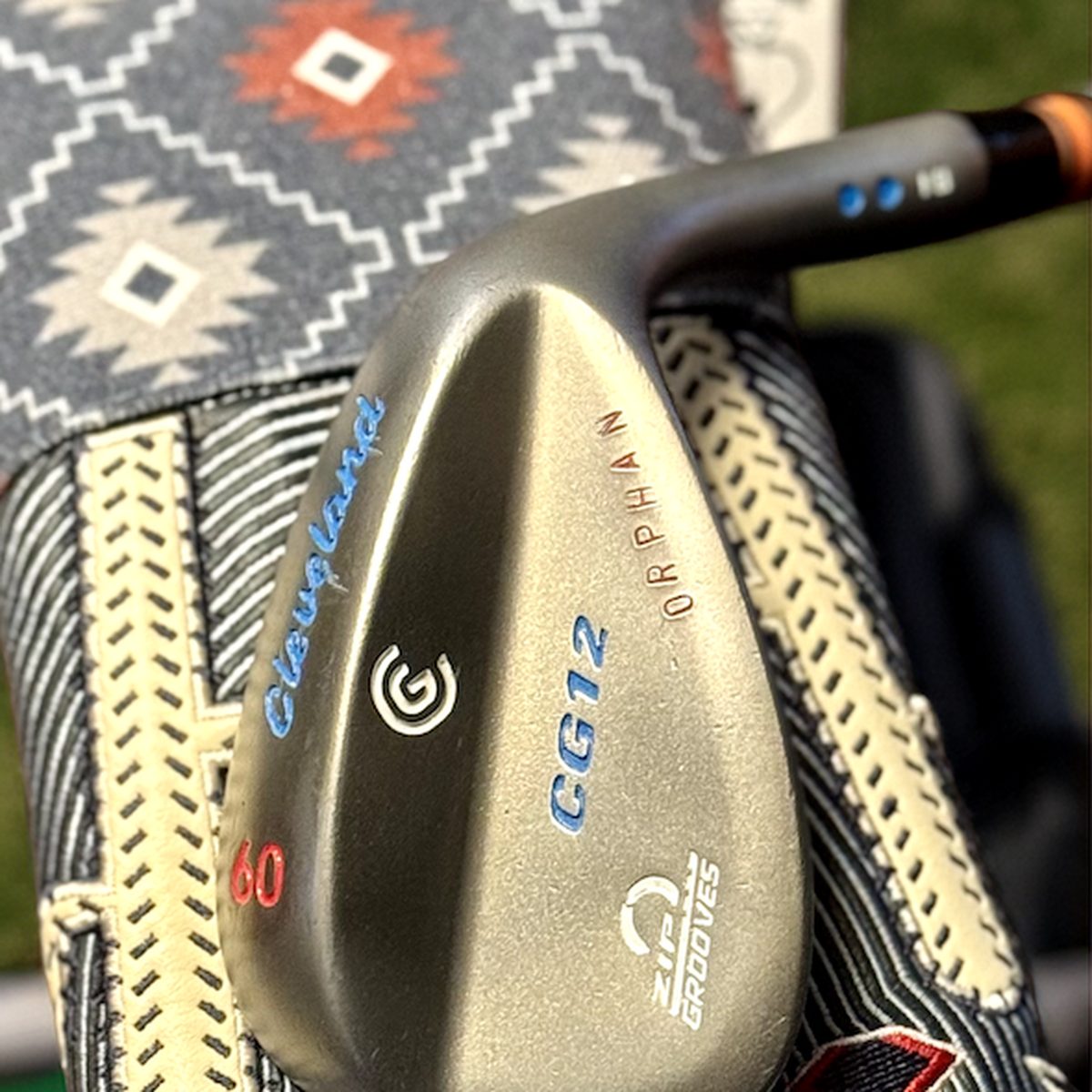 Cleveland CG12 wedge with custom ORPHAN stamping and blue paint fill, on a patterned headcover