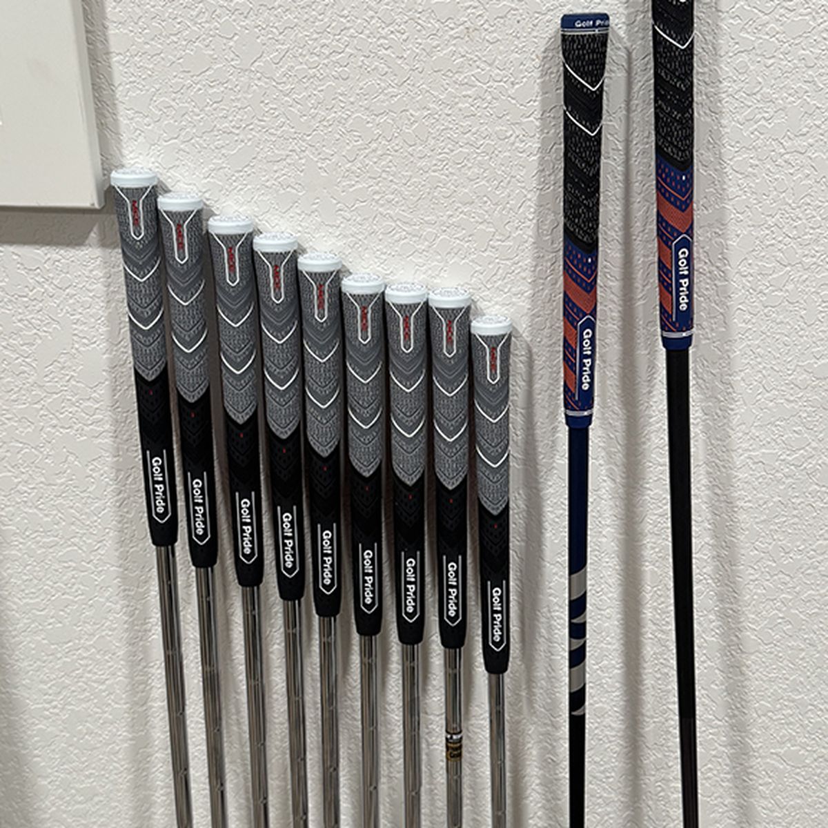 Iron set freshly regripped with new Golf Pride grips, lined up in the shop